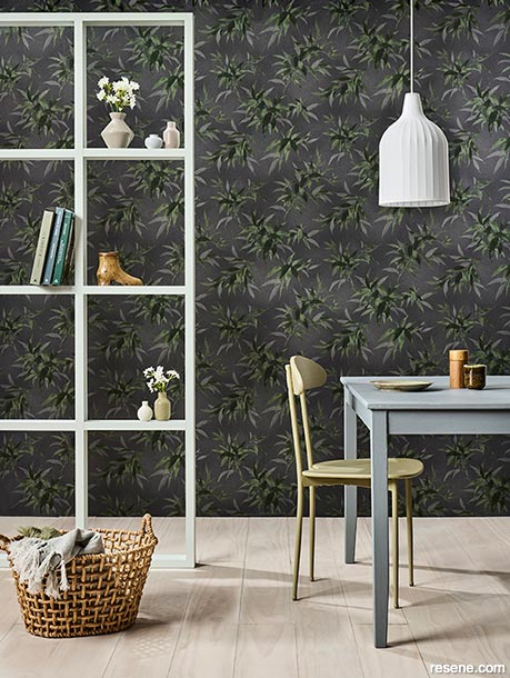 A dining room with dark leaf print wallpaper